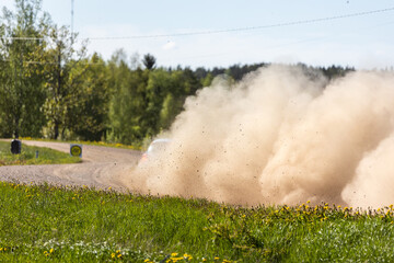 Rally racing car spraying dust and gravel behind.