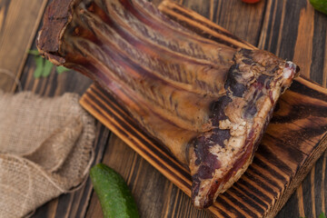 Pork ribs with spices, tomatoes and herbs on a wooden background. Smoked ribs. 