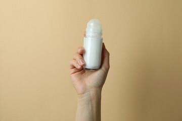 Female hand holds blank deodorant on beige background - obrazy, fototapety, plakaty