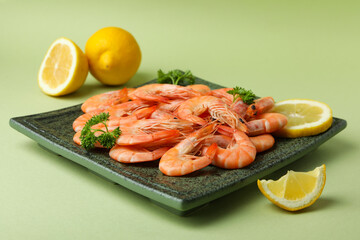 Plate with tasty shrimps on green background