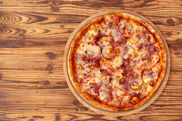 Top view of freshly baked pizza on wooden background