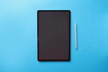Modern touch tablet with stylus lies on blue background