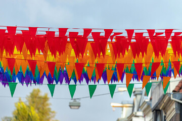 Celebration of Gay Pride in Amsterdam with rainbow flags hanging outside building along street, LGBT annual festival to celebrate that we can be who we are and love, Netherlands.