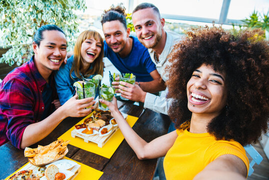Multiracial friends taking selfie at bar restaurant - Young people having fun together celebrating happy hour on cocktail pub - Friendship, youth and summer concept