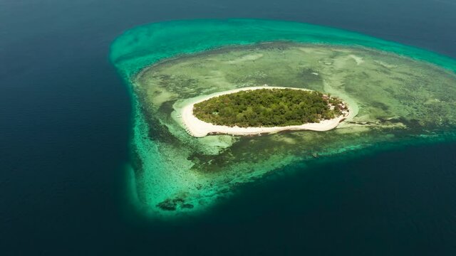 Tropical island in the blue sea with coral reef, top view. Small island with sandy beach. Summer and travel vacation concept, Mantigue island, Philippines, Mindanao
