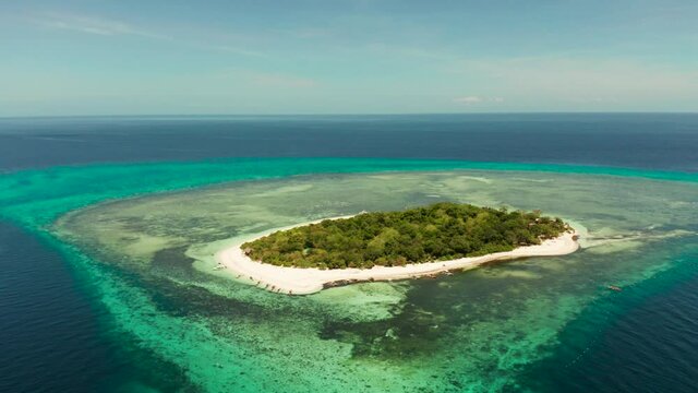 Tropical island in the blue sea with coral reef, top view. Small island with sandy beach. Summer and travel vacation concept, Mantigue island, Philippines, Mindanao