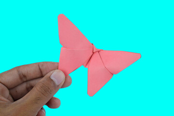 Pink butterfly made with small craft paper and nicely placed on a paper background on hand