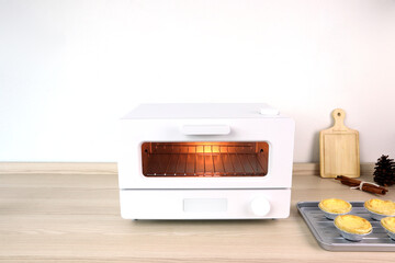 white modern design toaster oven is on the wooden table with homemade eggs tart on  white cement wall background in minimal design kitchen for making the breakfast