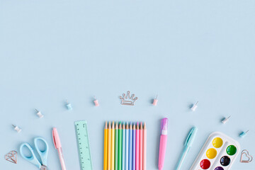 A frame of school supplies in pastel colors on a light blue background, space for text. Office supplies. Back to school. It was flat.