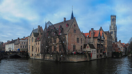 Fototapeta na wymiar Bruges cityscape. The old, medieval houses are placed near a canal. The bell tower can be seen in background. Belgium