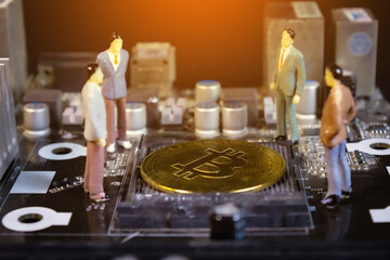 miniature business people stand around golden bitcoin on main board. crypto currency concept.closeup.
