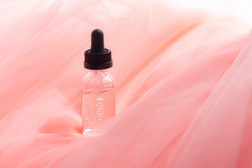 Hyaluronic acid bottle on coral fabric . Beauty container. Skin care. Vitamins for the skin....