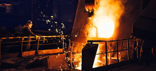 Molten metal pouring from blast furnace in foundry. Iron casting process in steel mill,...