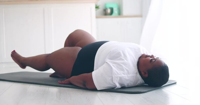 beautiful plus size woman exercising on sport mat at home