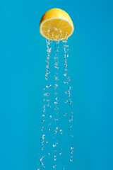 Lemon as a metaphor for a shower isolated on a blue background. Creative fruit food or drink...