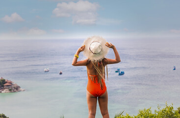 Fototapeta na wymiar Lifestyle young woman in red bikini and hat relax on the summer beach view background-Travel Holiday Concept
