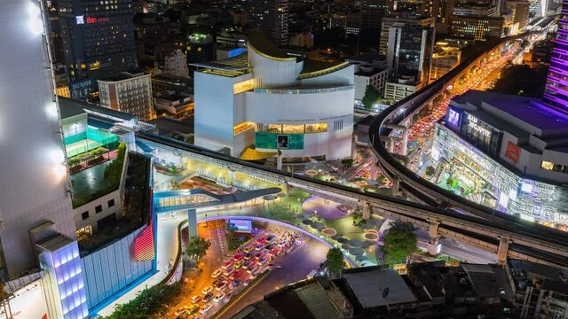 Time lapse of aerial view of Siam Bangkok Art and Culture Centre intersection or junction with cars traffic skyscraper buildings. Bangkok City in downtown at night, Thailand. 