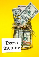 Dollars cash money and paper note with text written EXTRA INCOME. Concept of financial planning....