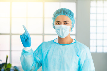 Fototapeta na wymiar asian male doctor in medical mask and pointing upper left corner