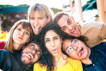 Multiethnic milenial people taking selfie sticking out tongue with happy faces - Funny life style and integration concept with interracial young friends having fun together - Powered by Adobe