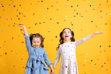 Adorable little children and falling confetti on yellow background