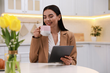 Young woman with tablet having breakfast in kitchen. Morning routine