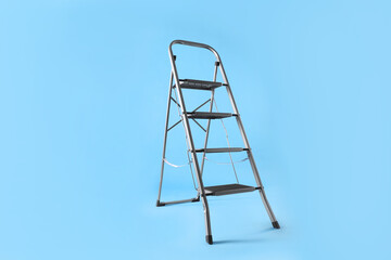 Metal stepladder on light blue background. Construction equipment