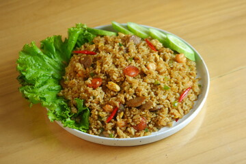 a plate of fried rice served with salad on a wooden table