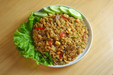 a plate of fried rice served with salad on a wooden table