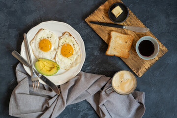 Fried eggs with toast, avocado, jam and coffee mug. Breakfast concept. Top view, flat lay. Tasty breakfast. Typical hotel breakfast. 