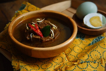 a bowl of black beef soup named rawon on the wooden table