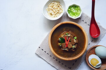 a bowl of black beef soup and the ingredient in white background 