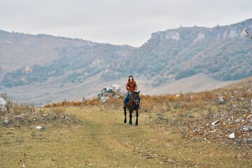 Fototapeta premium woman hiker in the mountains riding a horse adventure lifestyle