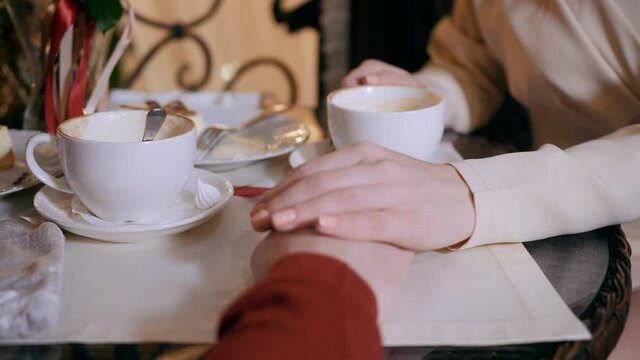 Close up female hand gently stroking male hands while romantic date in restaurant. Female hands touching male hand at restaurant table