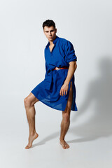 an attractive man in a blue dress on a light background in full growth lifted his leg up