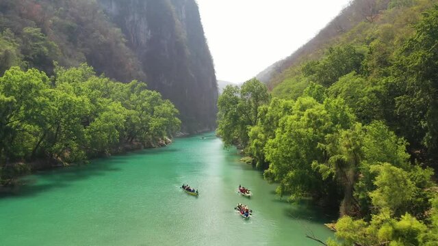 Aerial view of  boats in Tamasopo River, SAN LUIS POTOSI, Mexico. Green river flowing in a canyon. View from above