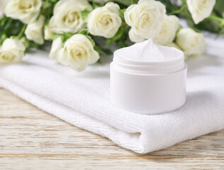 Fototapeta na wymiar Natural face cream or lotion sensitive skin, organic cosmetic product to moisturize the skin on a background of white roses.