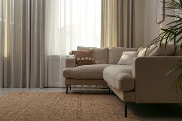 Modern comfortable sofa near window in stylish living room. Interior design