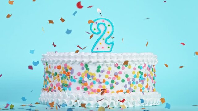 Birthday Cake With Burning Colorful Candle with Number 2 on Pastel Background. Falling confetti. Super Slow Motion, 1000 FPS.