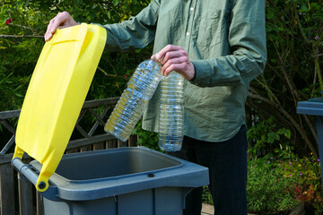 One person making a selective sorting of waste. Man putting plastic bottles in a yellow bin for...