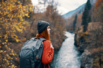 woman hiker with a backpack on her back near a mountain river in nature, back view