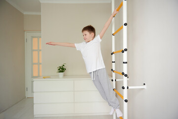 Fototapeta na wymiar Boy working out with wall bars at home,