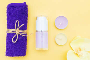 Aromatic candles, towel and lotion on a yellow background.
