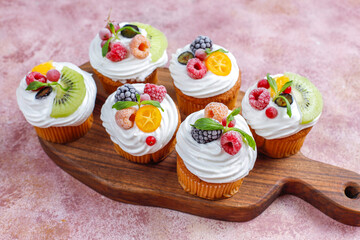 Homemade cupcakes with whipped cream and berries on top.
