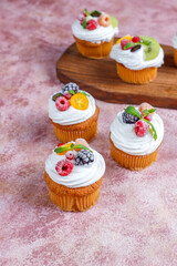 Homemade cupcakes with whipped cream and berries on top.
