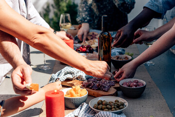people outdoor picking up food appetizer tapas from a long table with a glass bottle of wine in the...