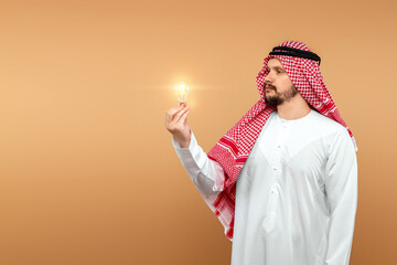 A man Arab holds a national costume holding a light bulb in his hand on a beige background. Concept...