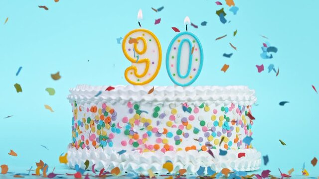 Birthday Cake With Burning Colorful Candles with Number 90 on Pastel Background. Falling confetti. Super Slow Motion, 1000 FPS.