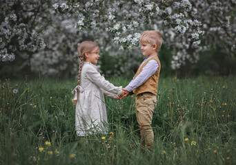 boy and girl stand in the apple orchard. boy holding the girl's hands. Love story