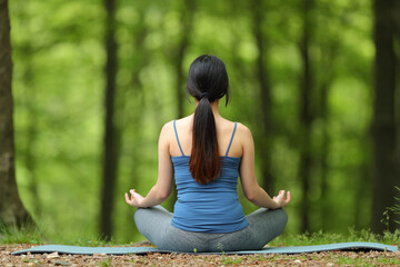Back view of a woman doing yoga in a forest